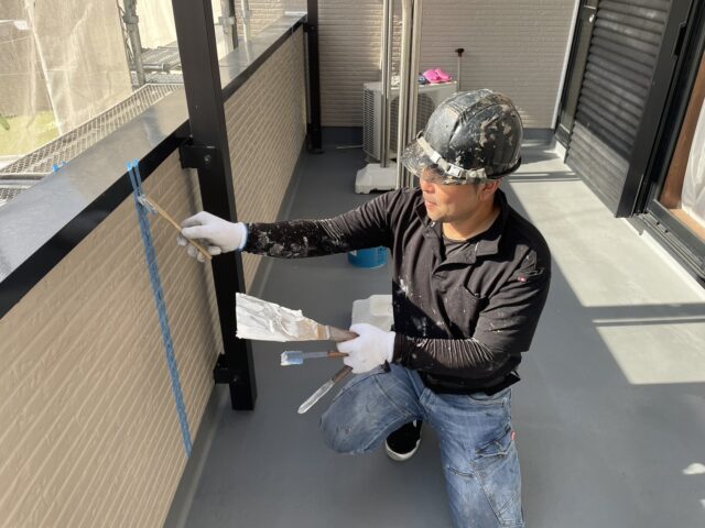 藤枝市の住宅でベランダ内壁を塗装する職人