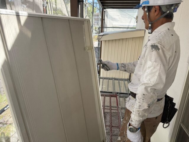 島田市の外壁塗装工事で雨戸に錆止め塗装を行う職人