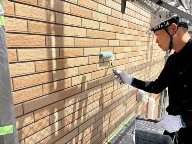 焼津市のサイディング外壁をクリヤ塗装している様子