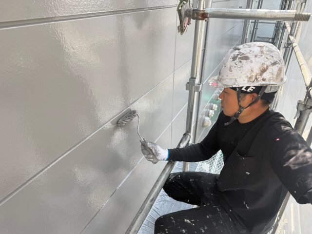 サイディング外壁の上塗りを丁寧に施工している様子