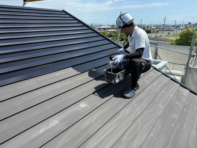 ガルバリウム鋼板屋根の下塗りを行う職人